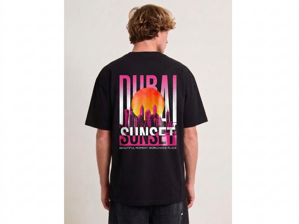 A man viewed from behind wearing a black t-shirt with a large graphic on the back featuring the text 'DUBAI SUNSET' and a colorful sunset design in pink, orange, and yellow.
